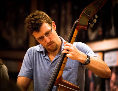 Earl, in blue golf shirt and wearing glasses, plays a standup bass.